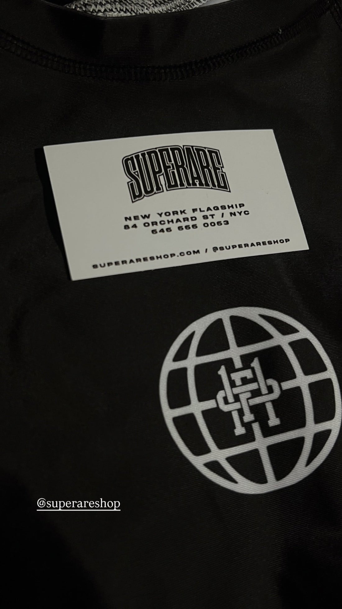 Close-up of SuperRare X Paragon Elite Fight tag with a globe logo, emphasizing fashion branding in New York.