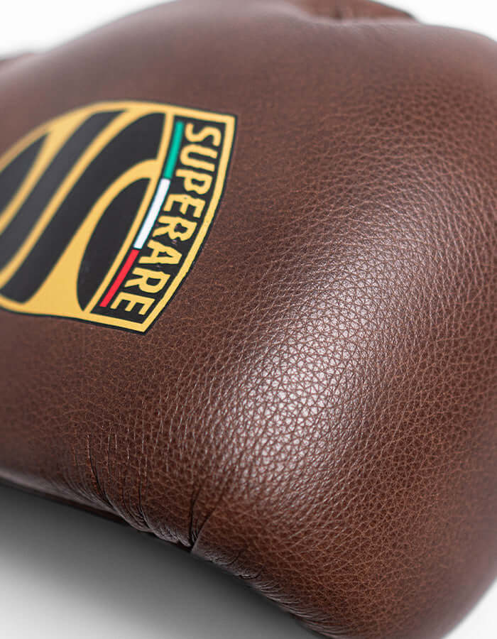 Close-up of Superare S50 boxing gloves in charcoal brown Italian leather, showcasing quality craftsmanship and logo.