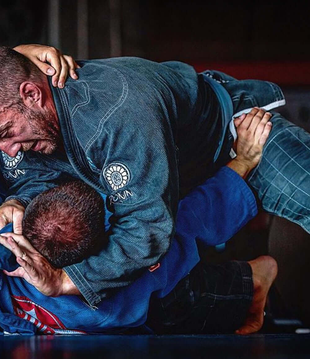 Two athletes grappling in Brazilian Jiu-Jitsu gi, showcasing technique and strength in BJJ and Boxing training.