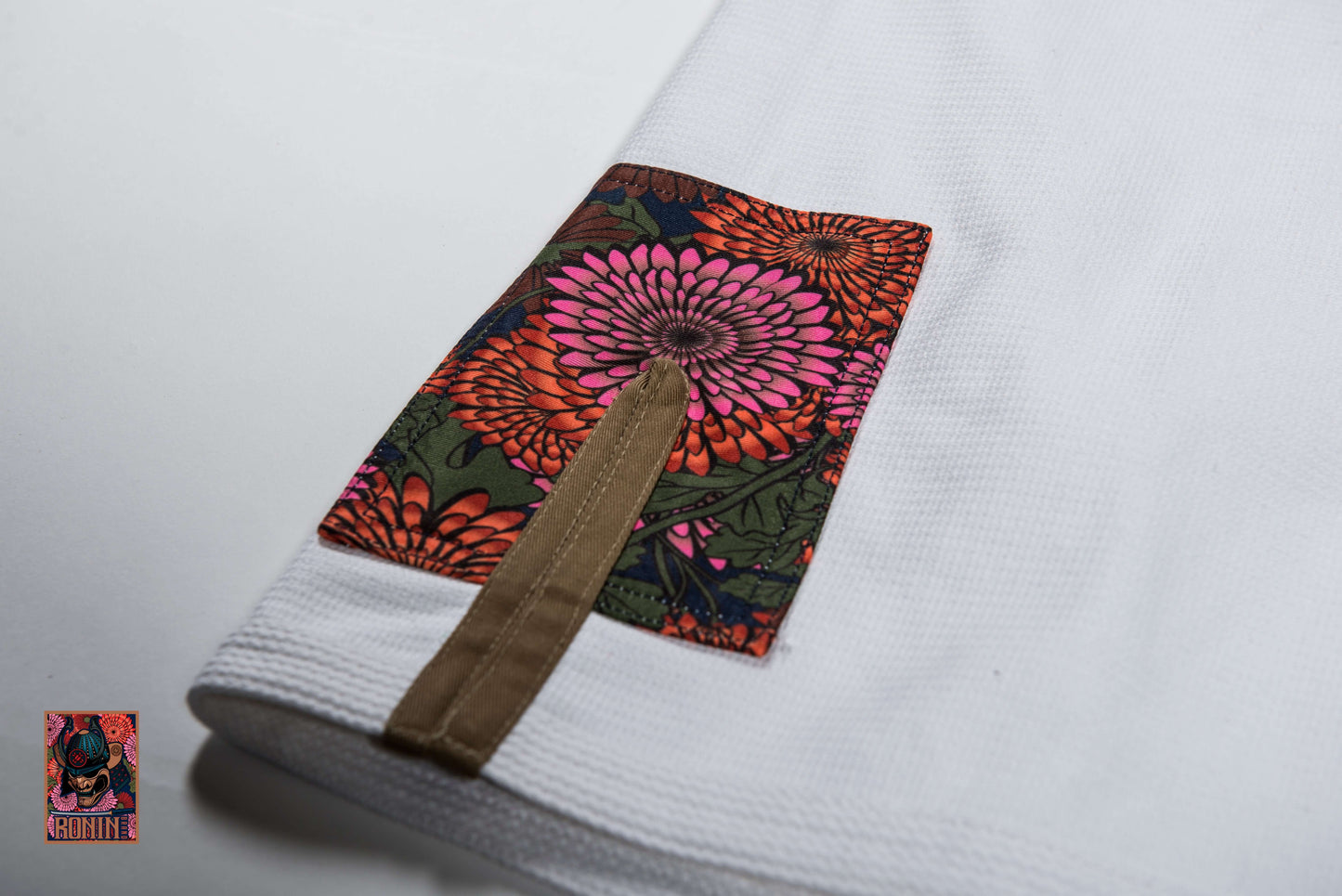 Close-up of the Roninbrand Emperor BJJ Gi's intricately embroidered sleeve with chrysanthemum design.