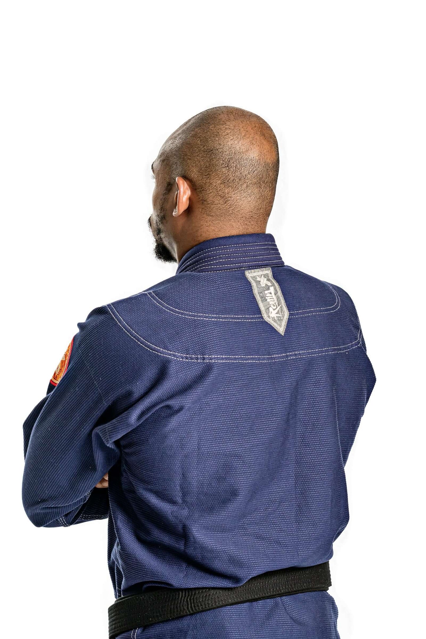 Person wearing Roninbrand Oni Bushi BJJ Gi in navy, showcasing the back design and black belt for Brazilian Jiu Jitsu.