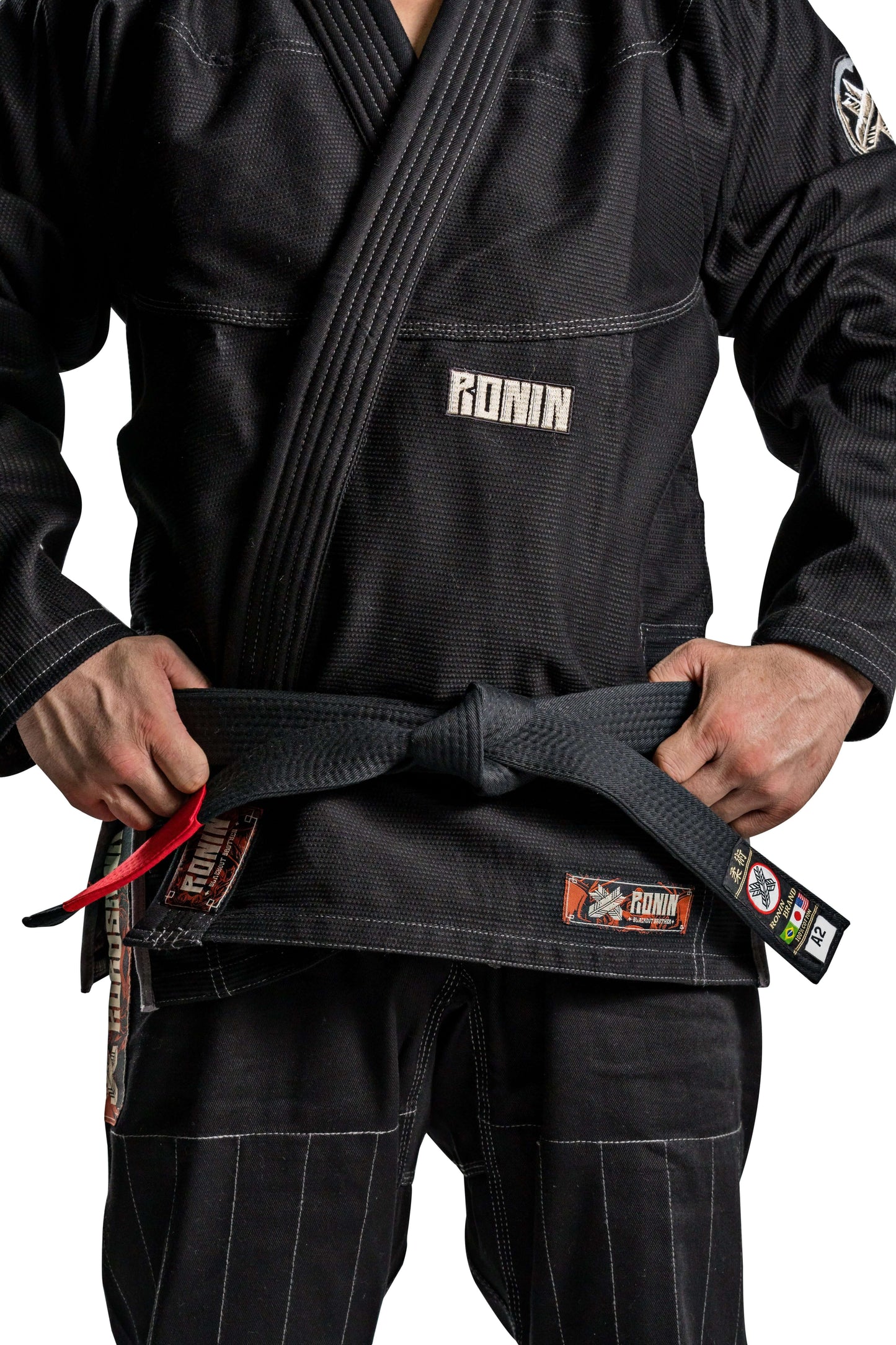 Roninbrand Kurosawa BJJ Gi in black with a fighter tightening their belt, symbolizing honor and legacy in Brazilian Jiu Jitsu.