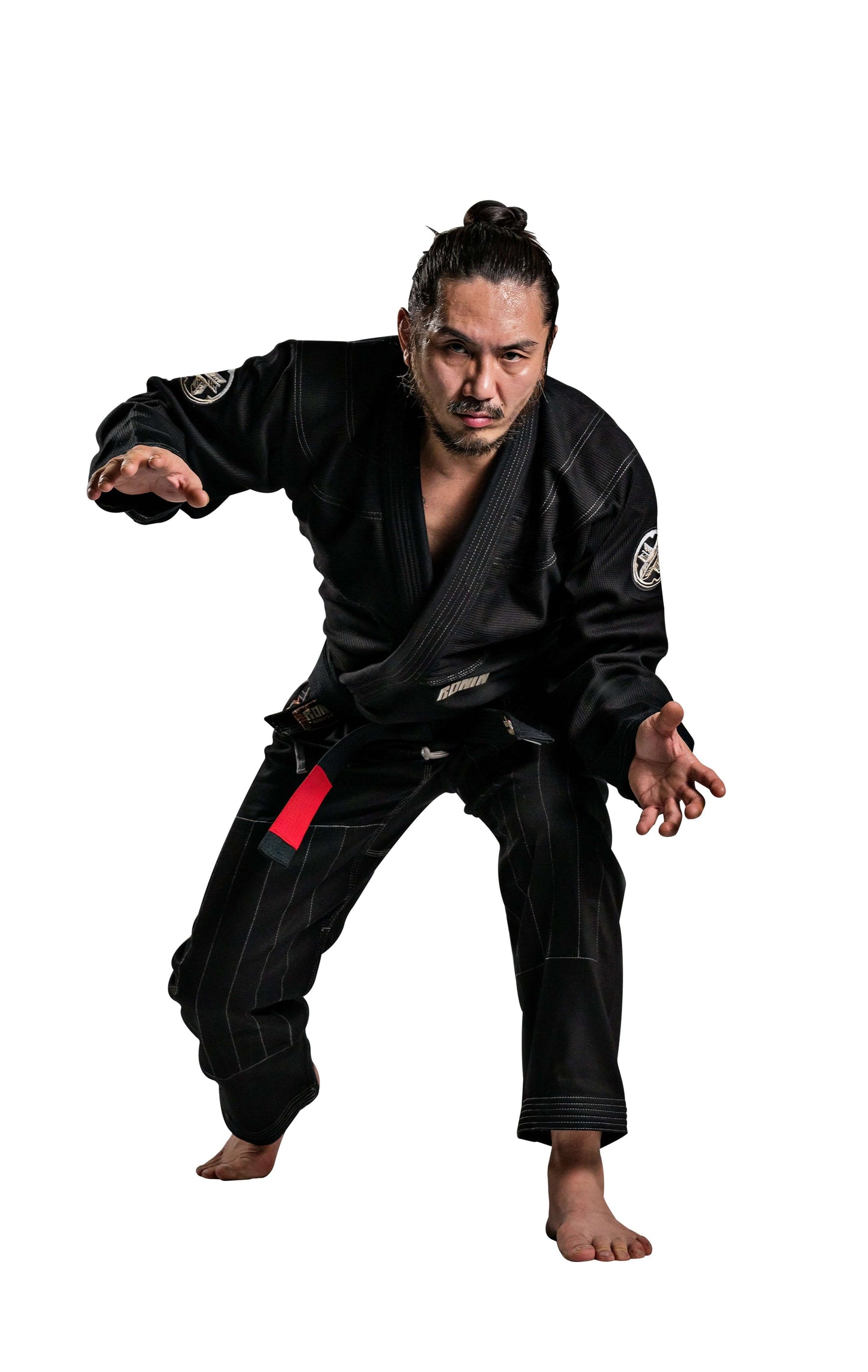 Man in black Roninbrand Kurosawa BJJ Gi performing martial arts pose with red belt, showcasing elite Brazilian Jiu Jitsu gear.