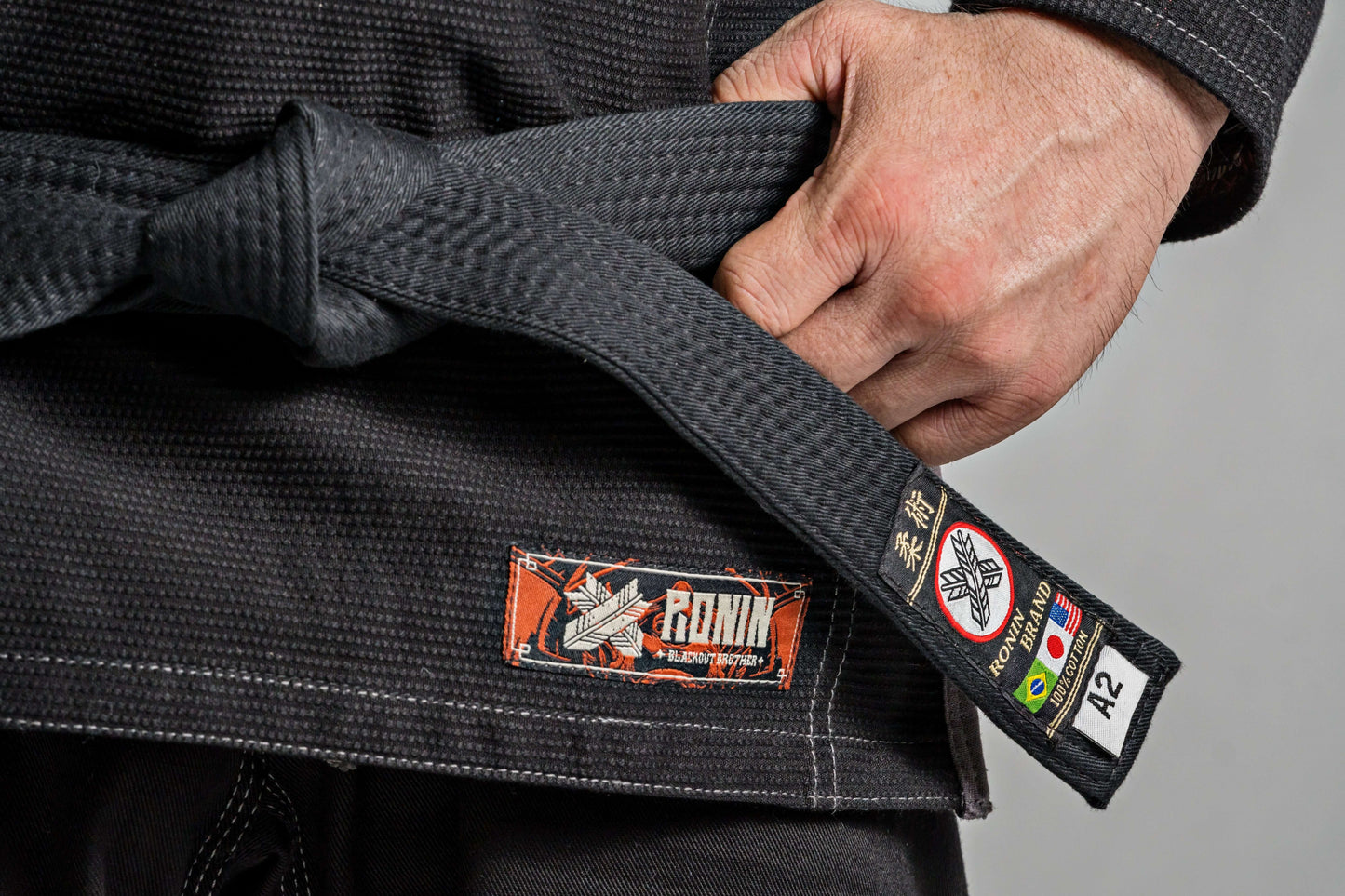 Close-up of Ronin Kurosawa BJJ Gi black fabric with Ronin logo and belt, showcasing quality for Brazilian Jiu Jitsu athletes.
