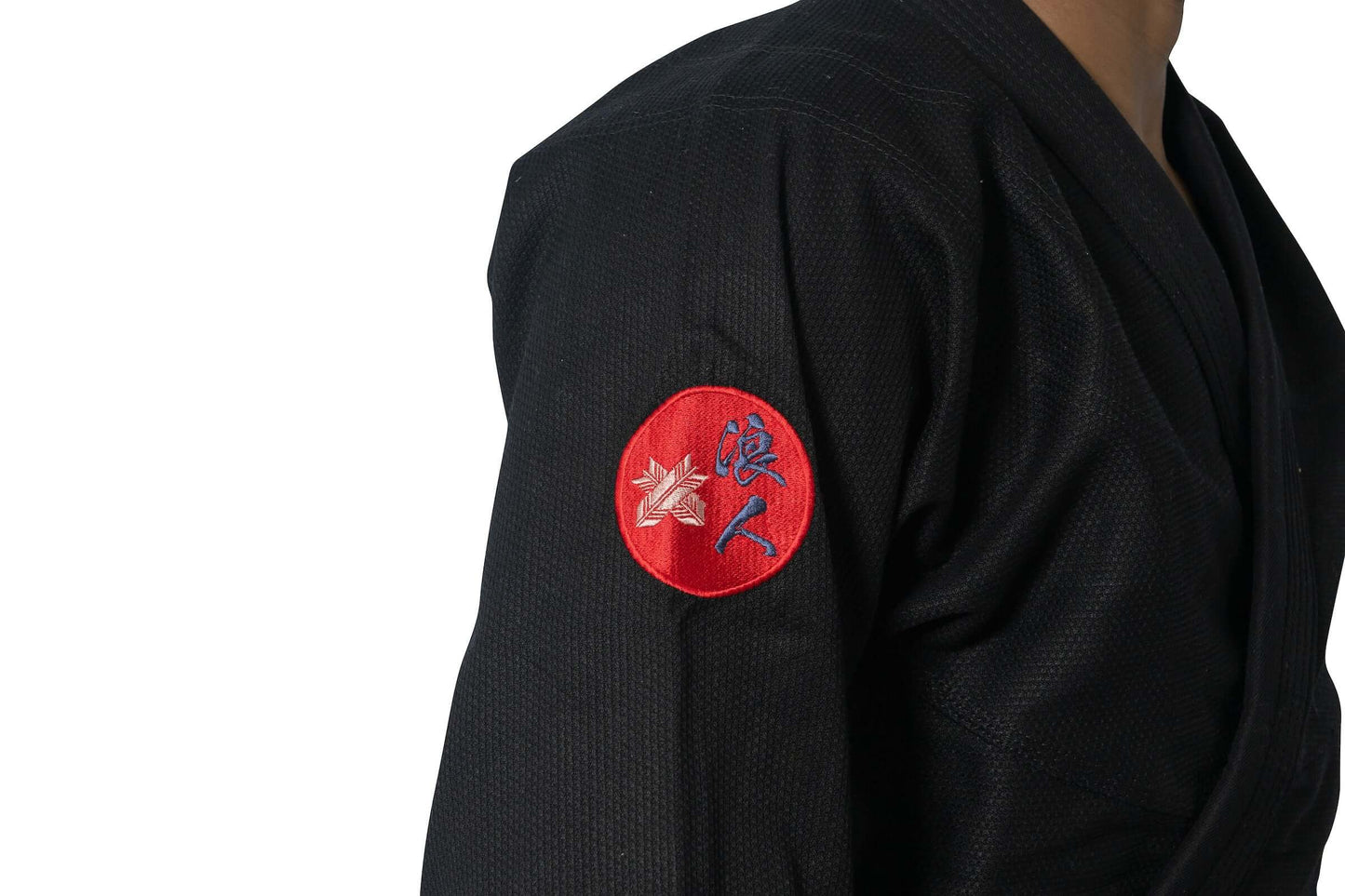 Close-up of Roninbrand Shinsei Yūgure BJJ Gi sleeve with embroidered logo on black fabric.
