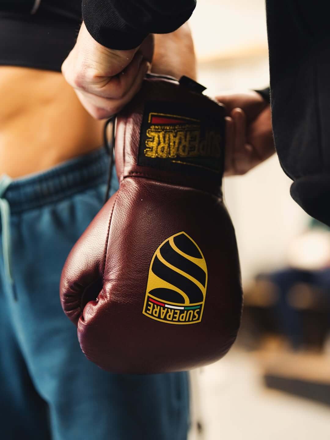 Close-up of a person putting on boxing gloves in a training setting, emphasizing boxing gloves.