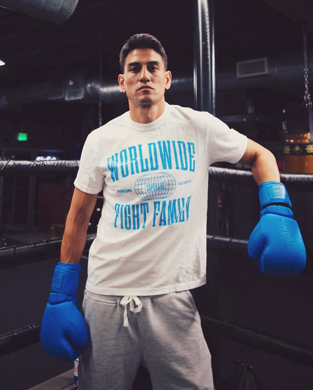 Athlete in blue boxing gloves promoting Paragon Elite Fight gear in training gym.
