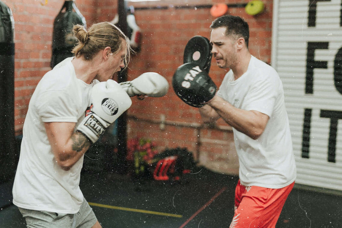 Boxing scene with two fighters practicing techniques, highlighting the importance of professional boxing gloves.