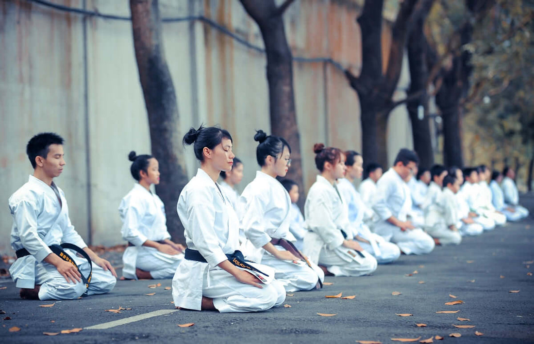 Martial artists practicing in traditional fight gear during a training session outdoors.