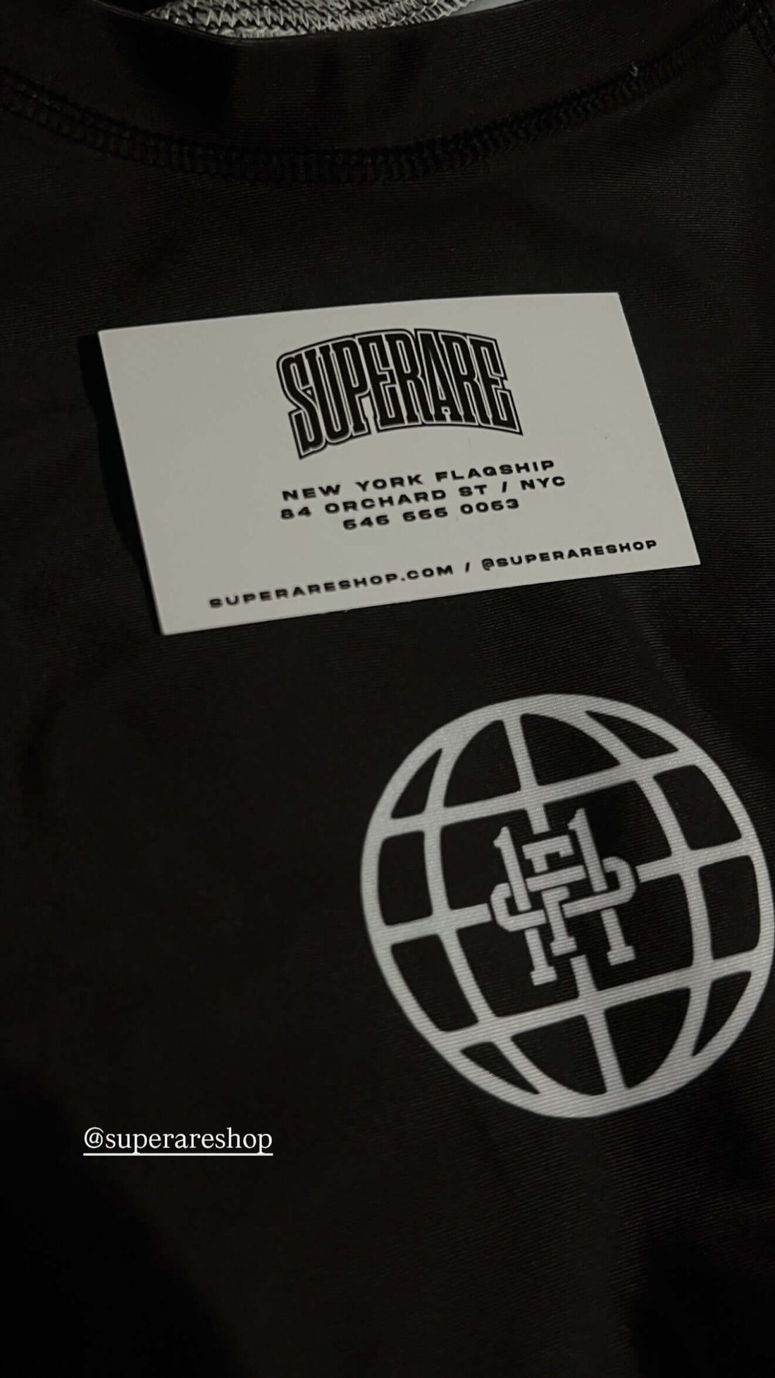 Close-up of SuperRare X Paragon Elite Fight  tag with a globe logo, emphasizing fashion branding in New York.