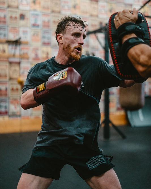 Boxing training session featuring athlete wearing boxing gloves, representing Boxing history and technique in the gym.