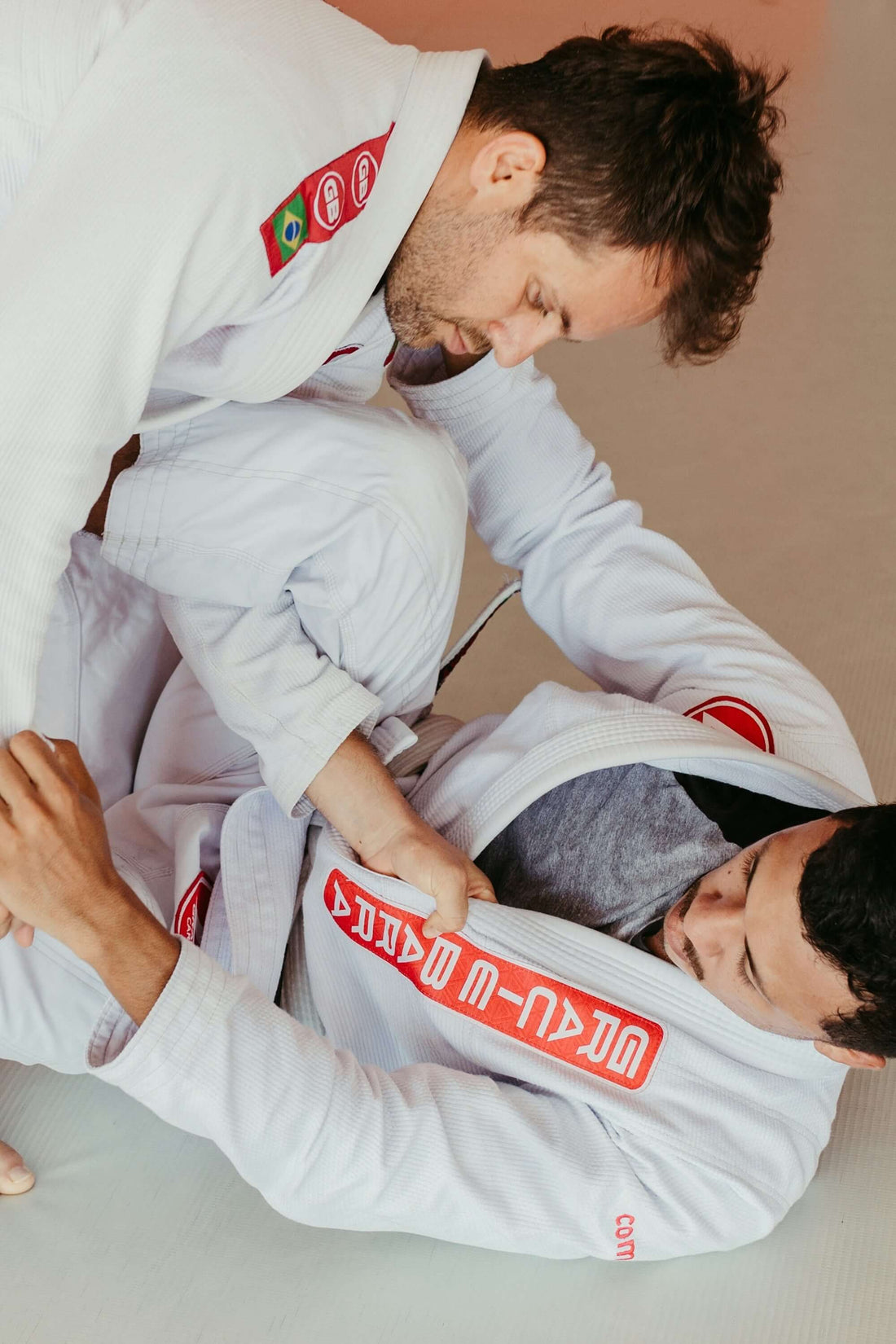 Two martial artists training in precision BJJ gi for frame strength techniques on the mat.