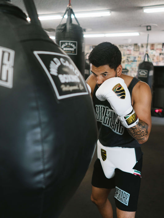 Boxing gloves used by a boxer training with a heavy bag in a gym setting, emphasizing skill and technique.