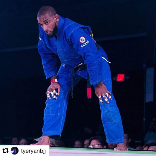 Jiu Jitsu practitioner wearing a blue BJJ gi, preparing for competition in a martial arts setting.