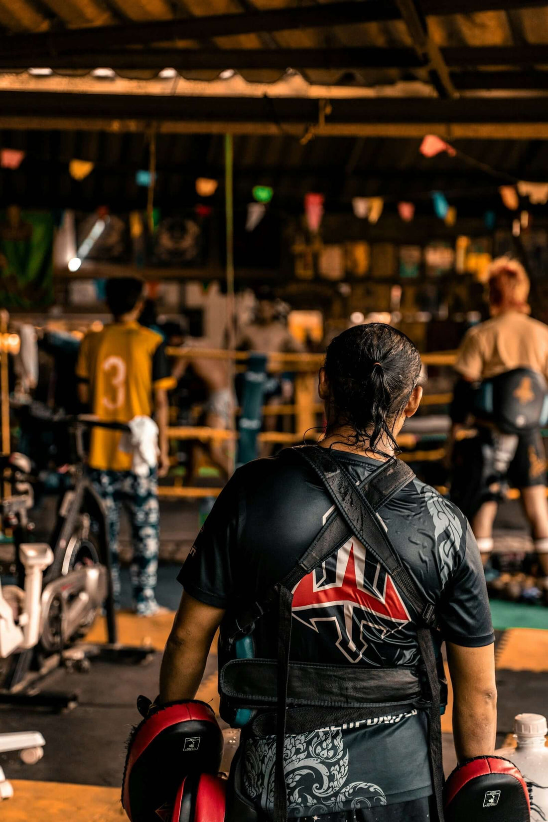 A fighter wearing a Jiu Jitsu Gi prepares for training in a gym setting.