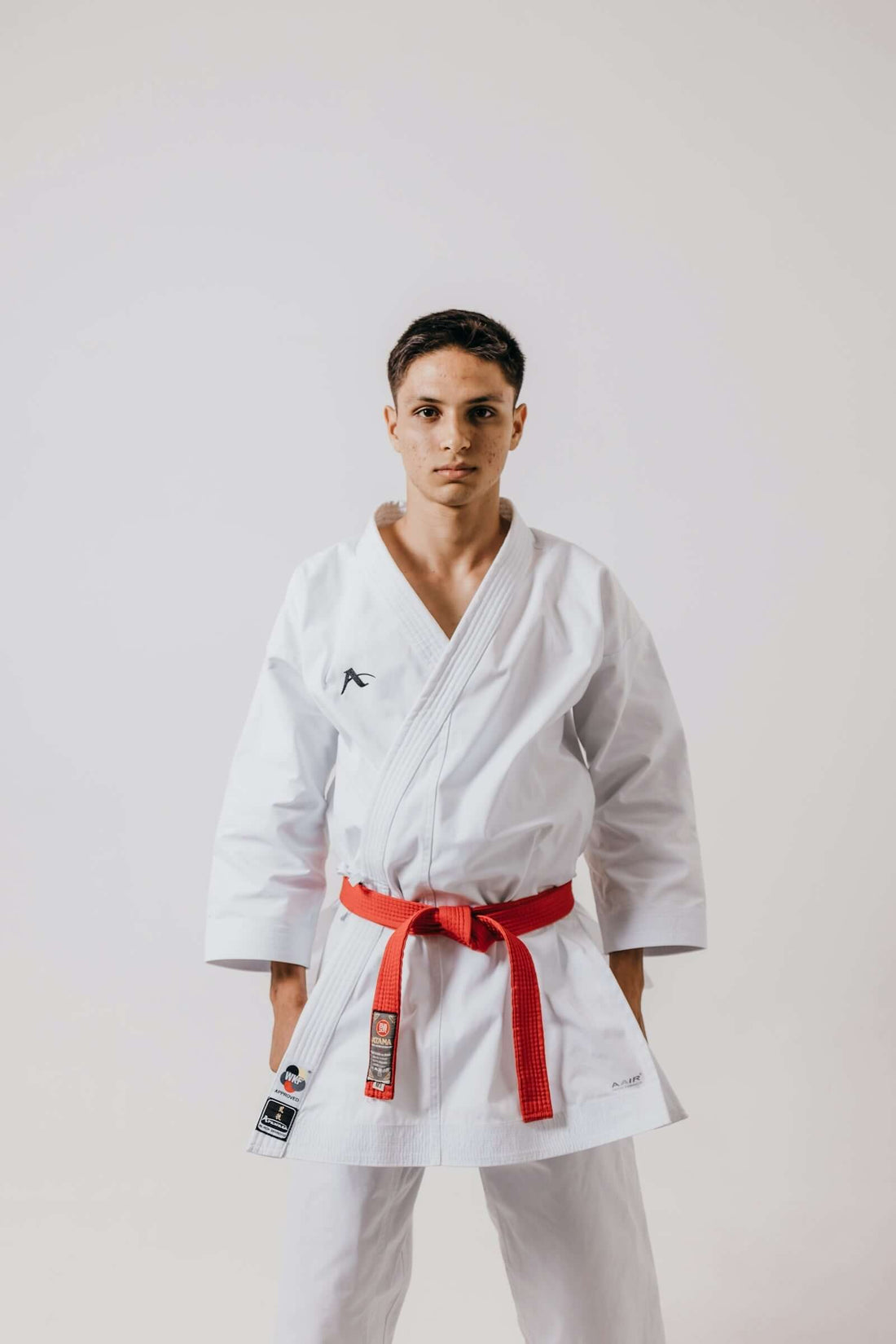 A young male martial artist wearing a white gi and red belt, demonstrating his readiness for fighting.