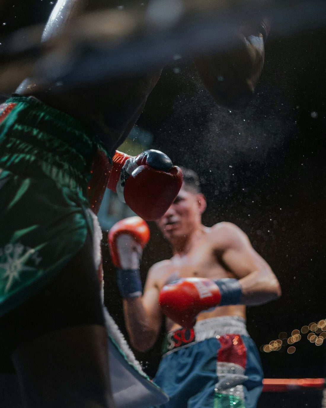 Fight scene featuring two boxers in a ring, showcasing competition boxing gloves and intense action.