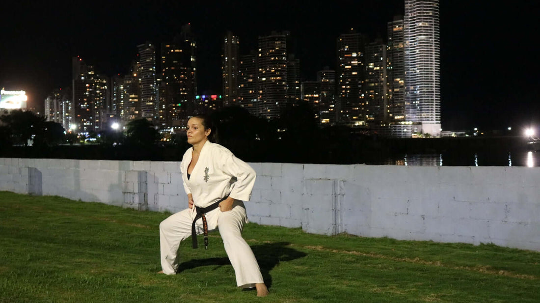 BJJ practitioner demonstrating techniques outdoors at night with a city skyline in the background.