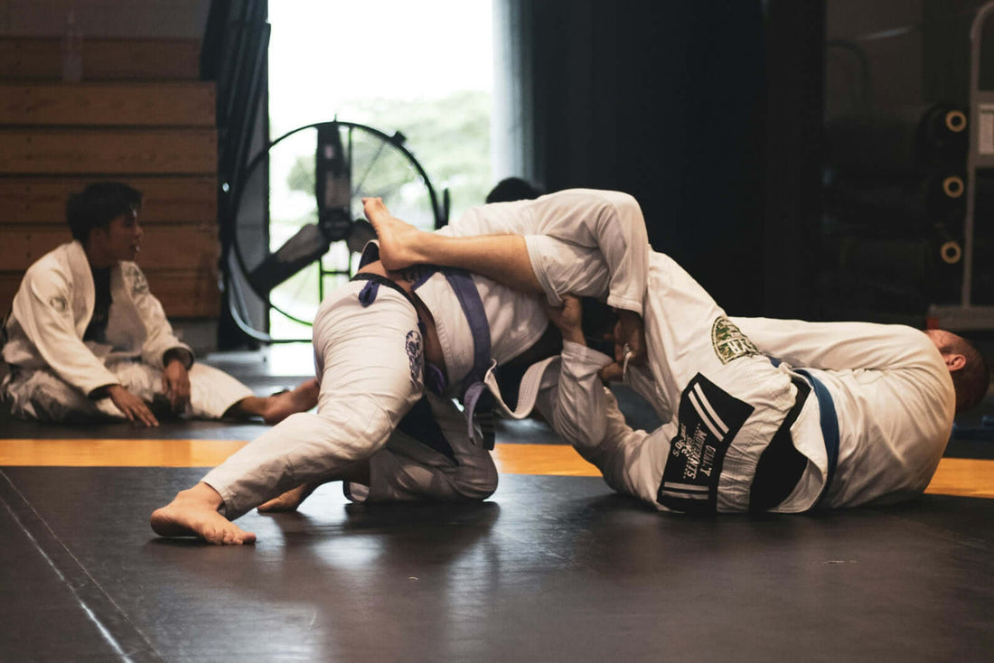 BJJ practitioners grappling on the mat, showcasing techniques and strategies in a Brazilian Jiu-Jitsu training session.
