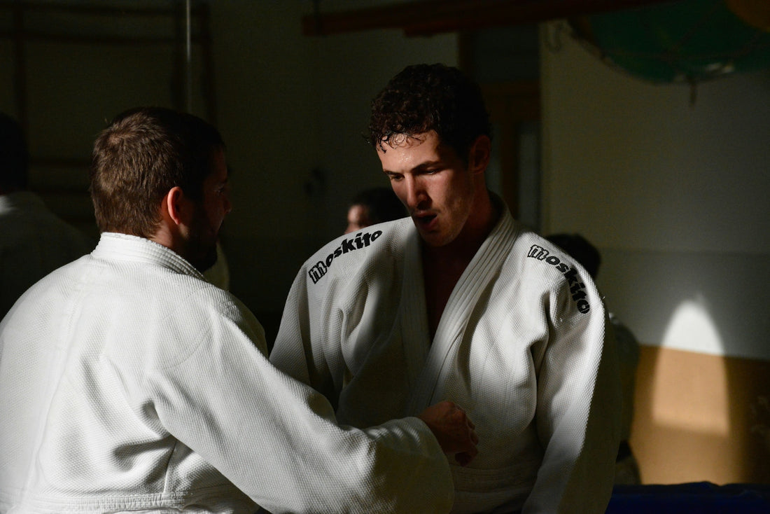 Fight: Two practitioners in professional BJJ gis training in a dojo, demonstrating techniques and martial arts skills.