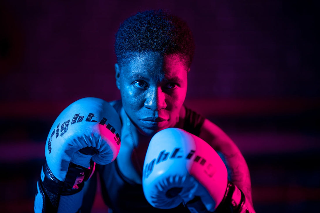 A boxer in blue gloves ready to fight, illustrating the topic of boxing gloves vs BJJ gis.