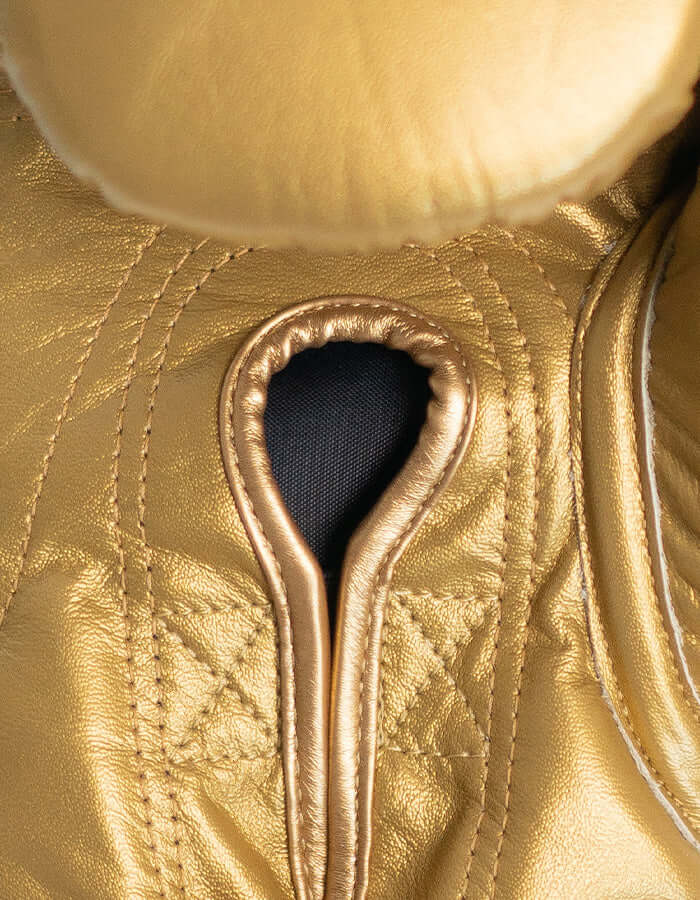 Close-up of Superare S50 gold boxing gloves showcasing premium Italian leather craftsmanship.