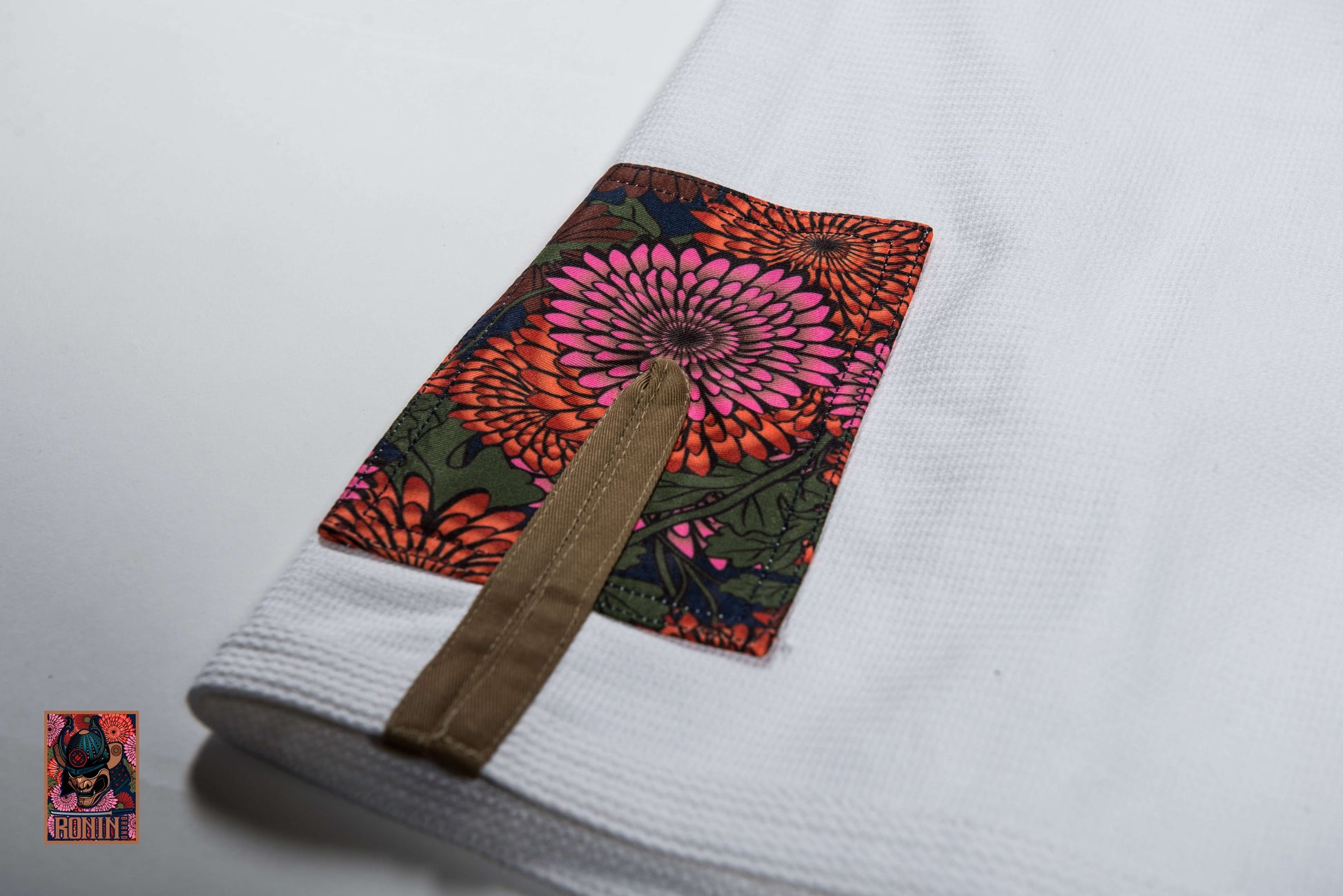 Close-up of the Roninbrand Emperor BJJ Gi's intricately embroidered sleeve with chrysanthemum design.