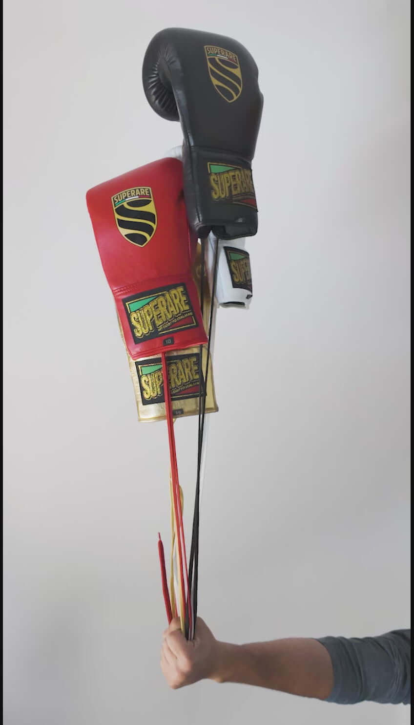Superare boxing gloves in red and black held by a hand, showcasing quality and design for professional fighters.