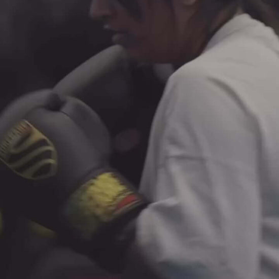Woman training with boxing gloves in a gym, showcasing dedication and strength in her workout.