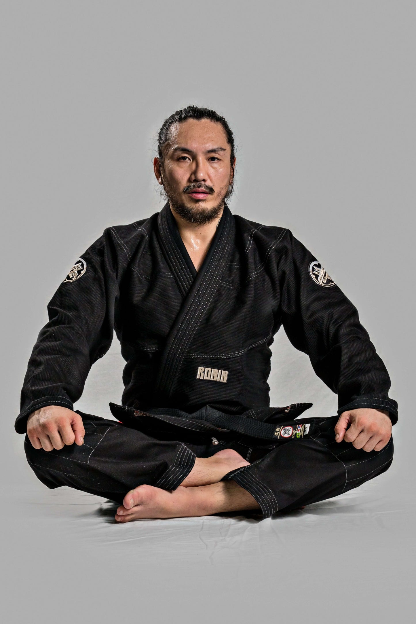 Roninbrand Kurosawa BJJ Gi in black worn by a martial artist sitting in a meditative pose, showcasing comfort and style.
