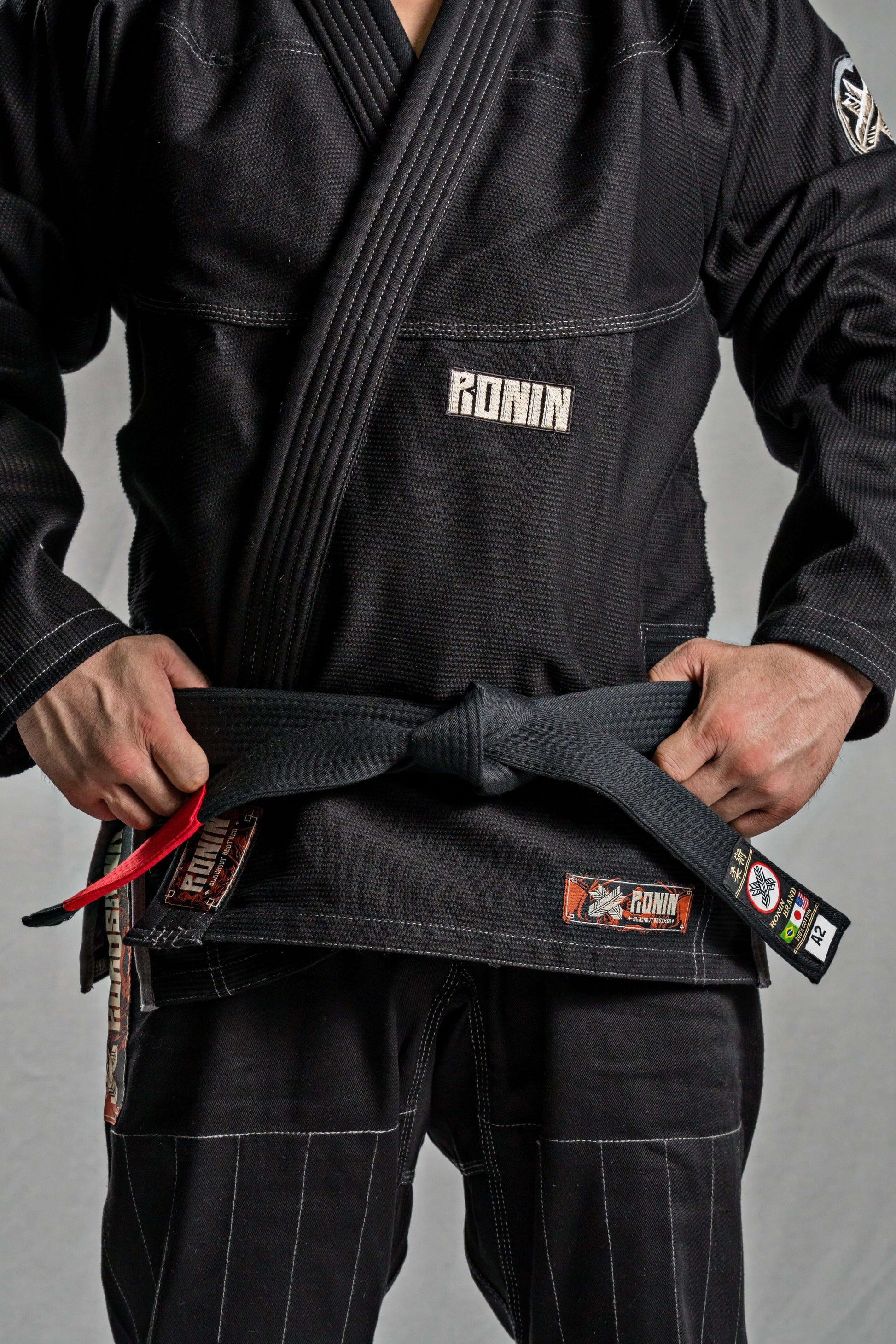 Close-up of a fighter in a black Roninbrand BJJ Gi, tying a black belt, showcasing premium craftsmanship and comfort.