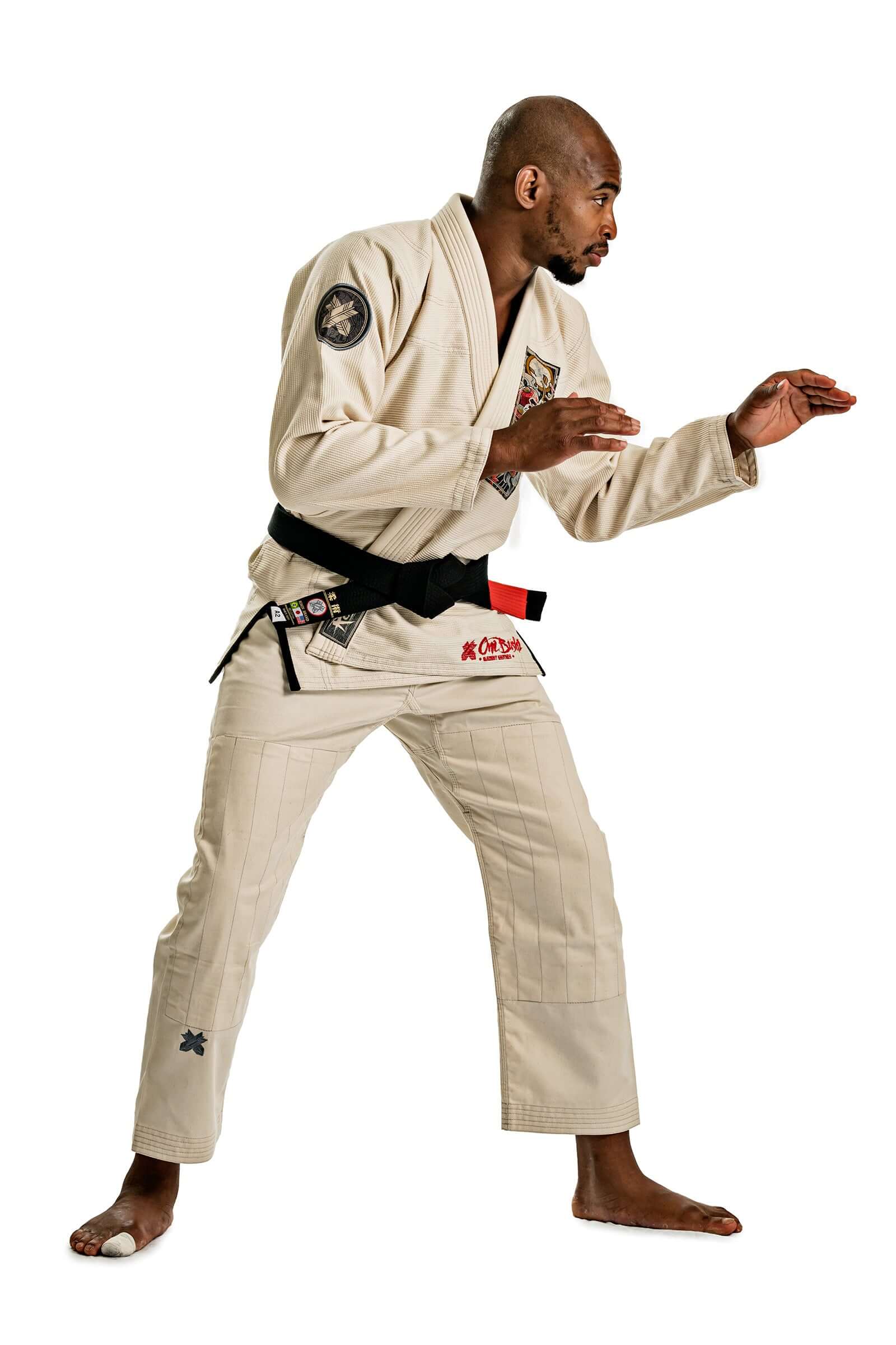 Model demonstrating Roninbrand Oni Bushi BJJ Gi in unbleached color, showcasing dynamic grappling stance.