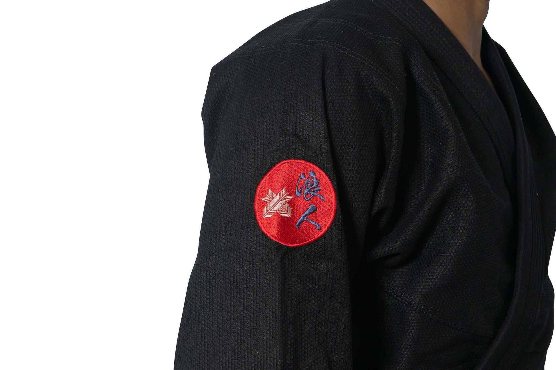 Close-up of Roninbrand Shinsei Yūgure BJJ Gi sleeve with embroidered logo on black fabric.