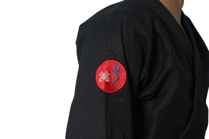 Close-up of Roninbrand Shinsei Yūgure BJJ Gi sleeve with embroidered logo on black fabric.